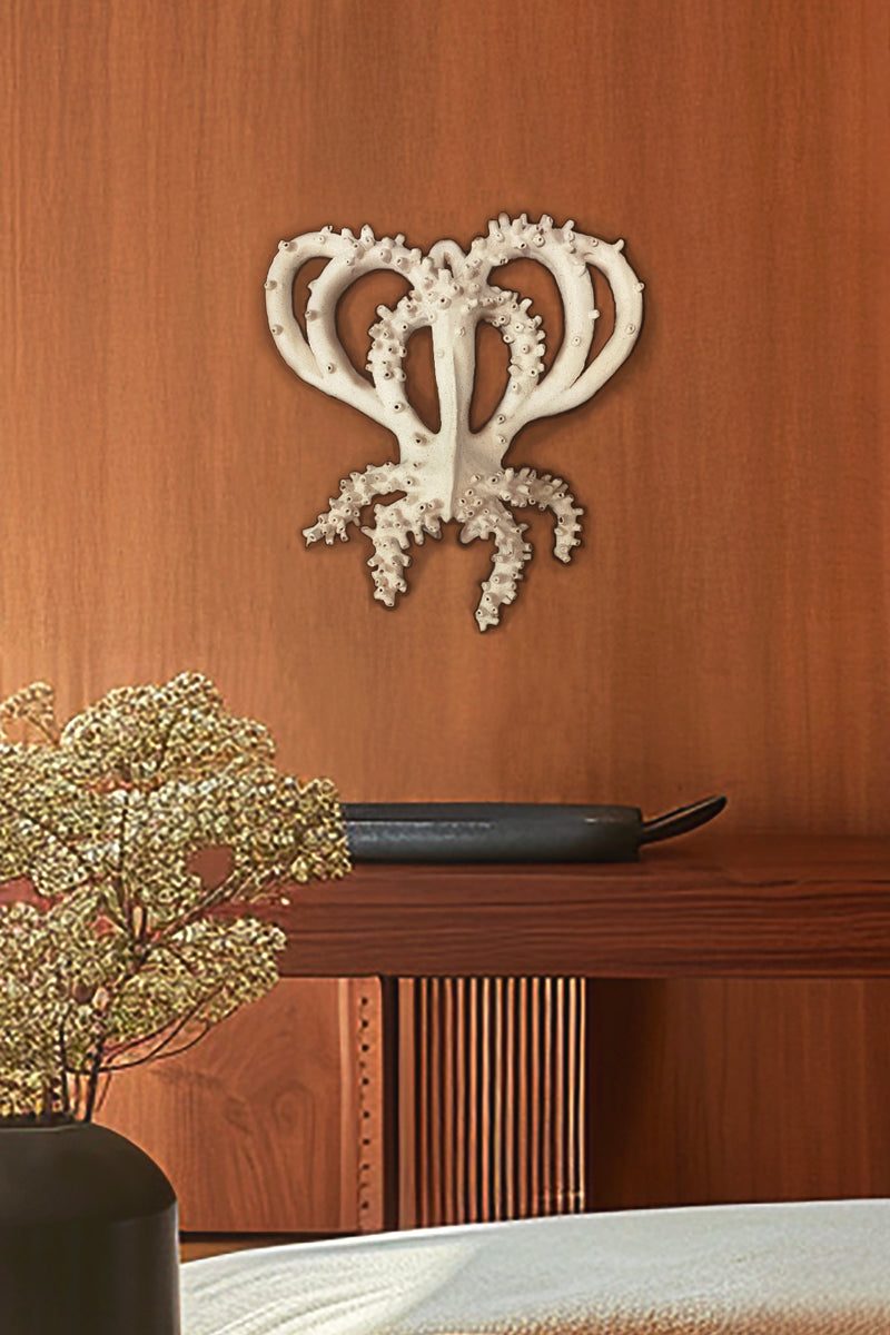 Sculpture murale en faïence blanche de l'artiste Chi Phan, représentant une forme organique aquatique. Elle est présentée sur un mur en bois, au dessus d'une console en bois, dans un intérieur élégant et minimaliste.