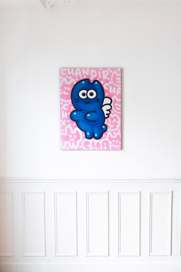 "CHA ANGE” – Œuvre contemporaine de CHANOIR, représentant un chat bleu ailé sur fond rose graphique, accrochée dans un intérieur élégant avec moulures blanches et parquet en bois. Idéal pour une décoration murale moderne mêlant street art et design d’intérieur haut de gamme. Parfait pour les architectes d’intérieur et les décorateurs cherchant des œuvres d’art audacieuses pour des projets résidentiels ou commerciaux.