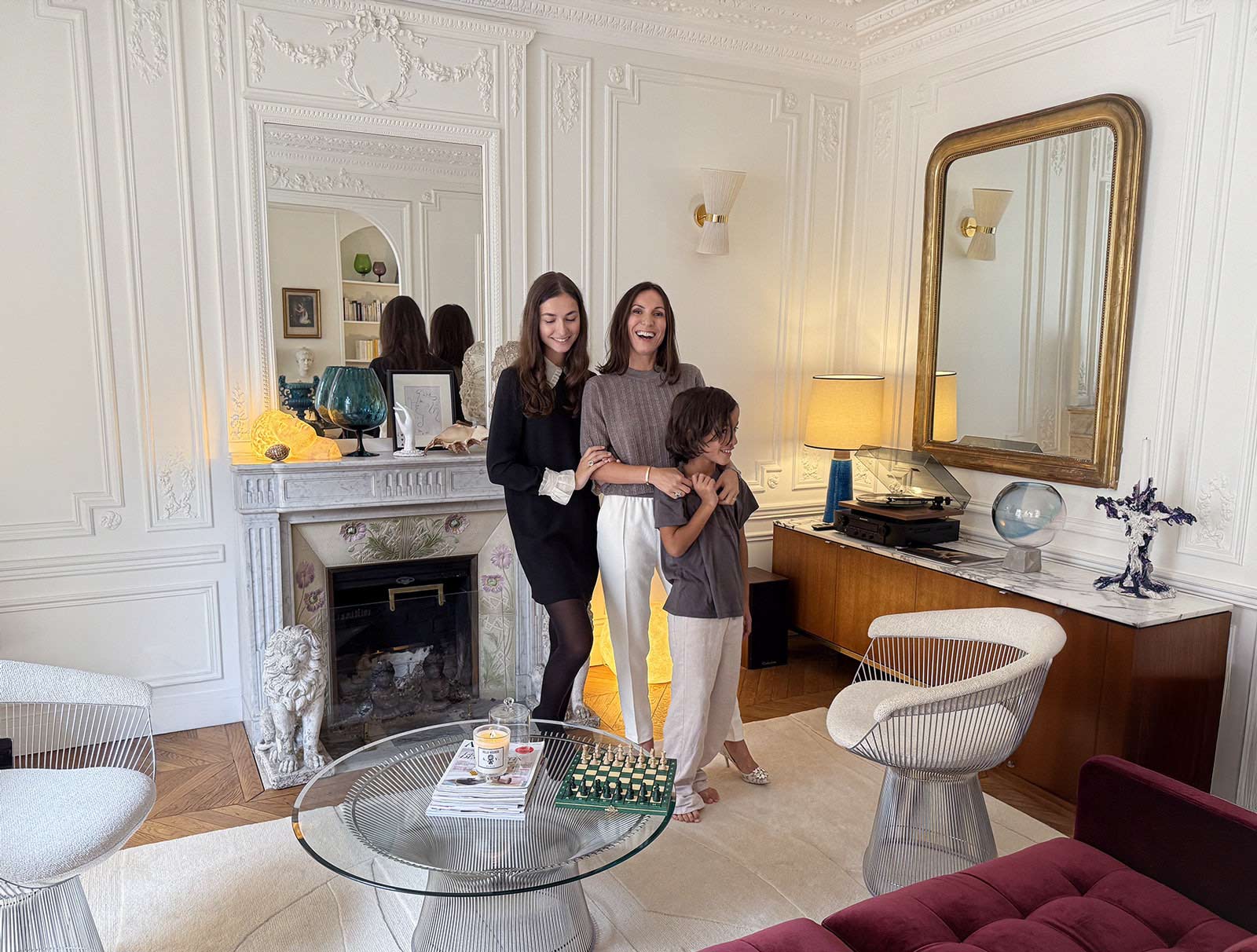 Intérieur haussmannien à Paris, une collectionneuse d’art avec ses deux enfants dans un salon design ; cheminée en marbre, fauteuils Platner, œuvres contemporaines et mobilier vintage.