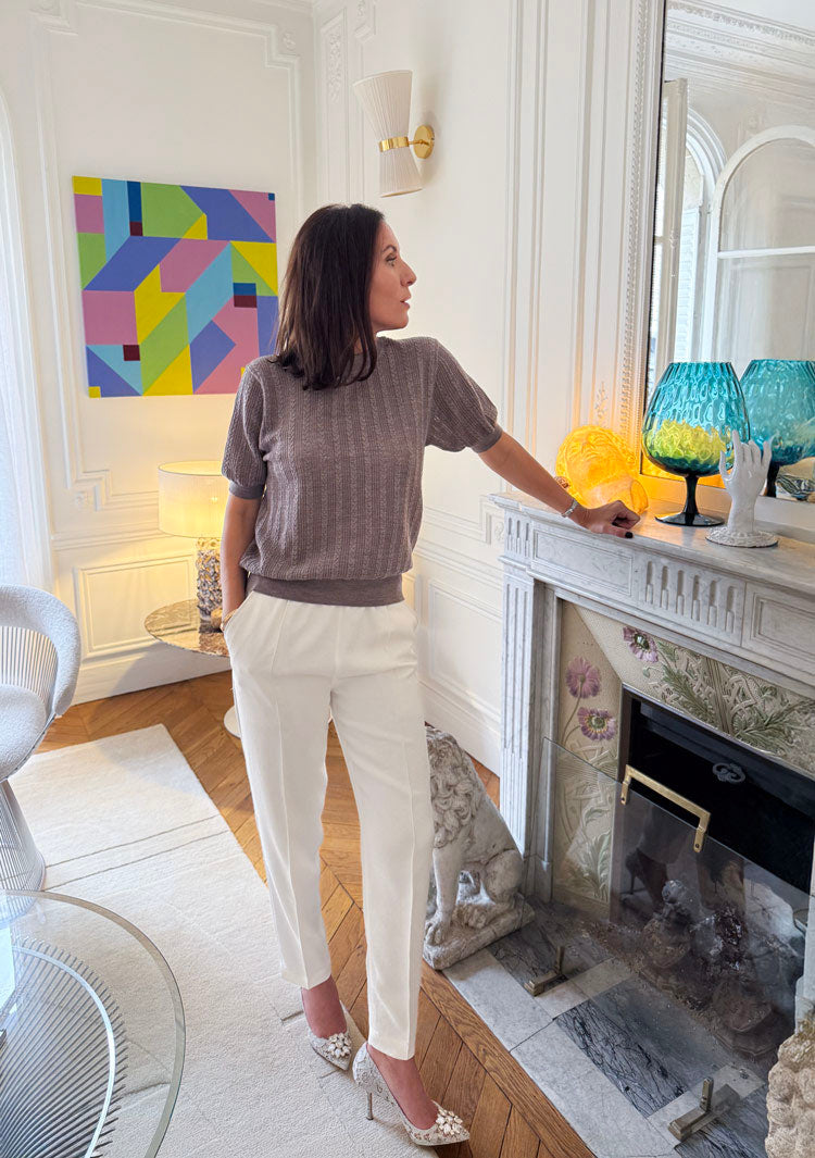 Collectionneuse d’art dans un salon haussmannien à Paris, devant une cheminée marbre et verre, œuvres contemporaines, vases colorés et tableau géométrique.