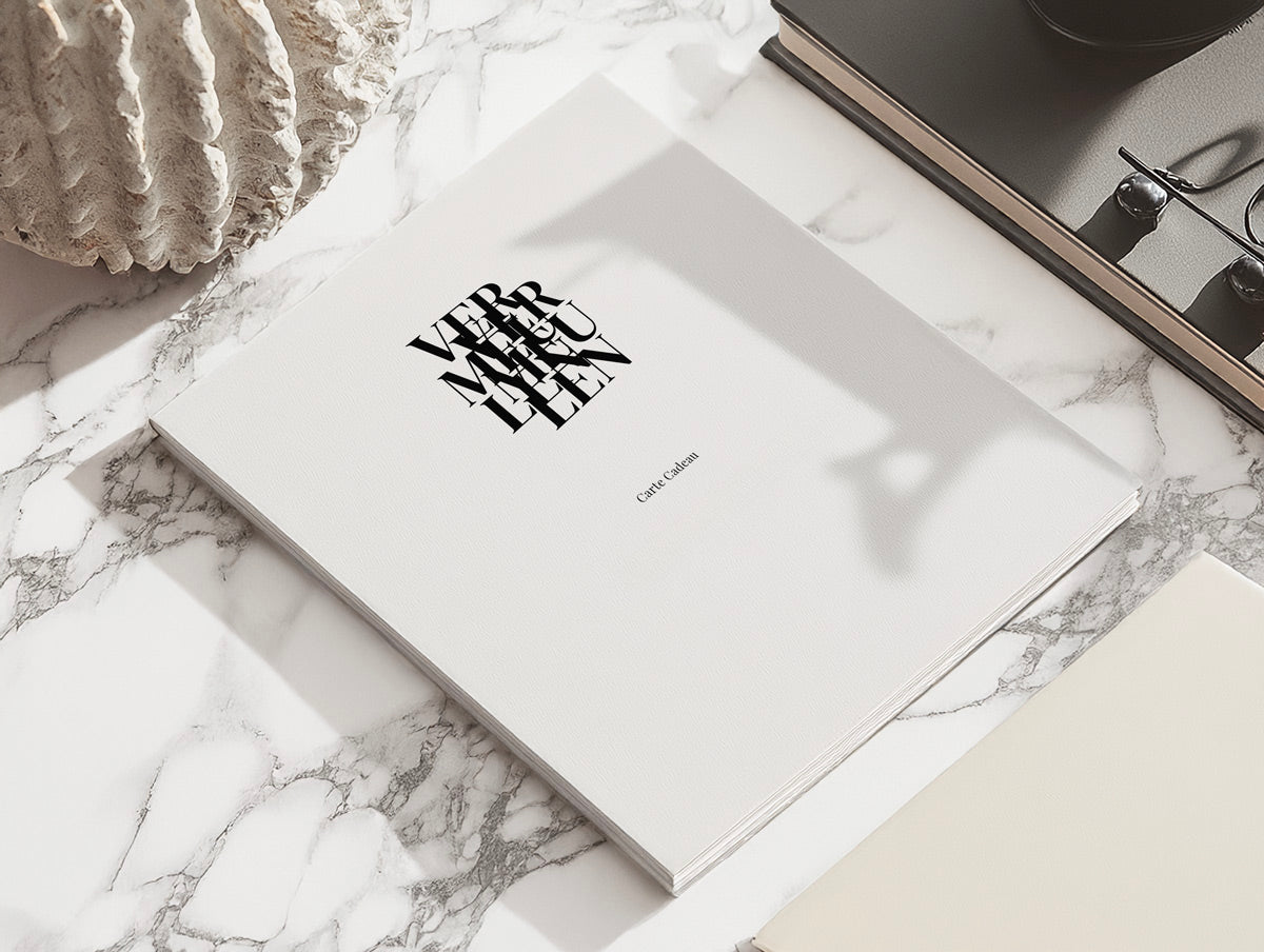 Carte cadeau Galerie Vermeulen posée sur un bureau en marbre– une invitation à offrir de l’art contemporain.