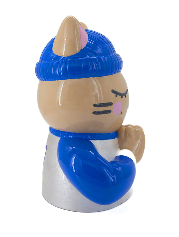 Vue de profil droit de la sculpture collector "Foi" par CHANOIR – œuvre originale. Chat beige aux yeux clos, coiffé d’un bonnet bleu vif et vêtu d’un t-shirt blanc nacré avec des manches bleu vif et bordures blanches. Pièce unique peinte à la main, art toy fusion de street art et art contemporain.