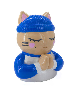 Vue trois-quarts droit de la sculpture "Foi" par CHANOIR – œuvre originale. Chat beige aux yeux clos, coiffé d’un bonnet bleu vif et vêtu d’un maillot blanc nacré avec manches bleu vif et bordures blanches. Pièce unique peinte à la main, fusion de street art et sculpture contemporaine.