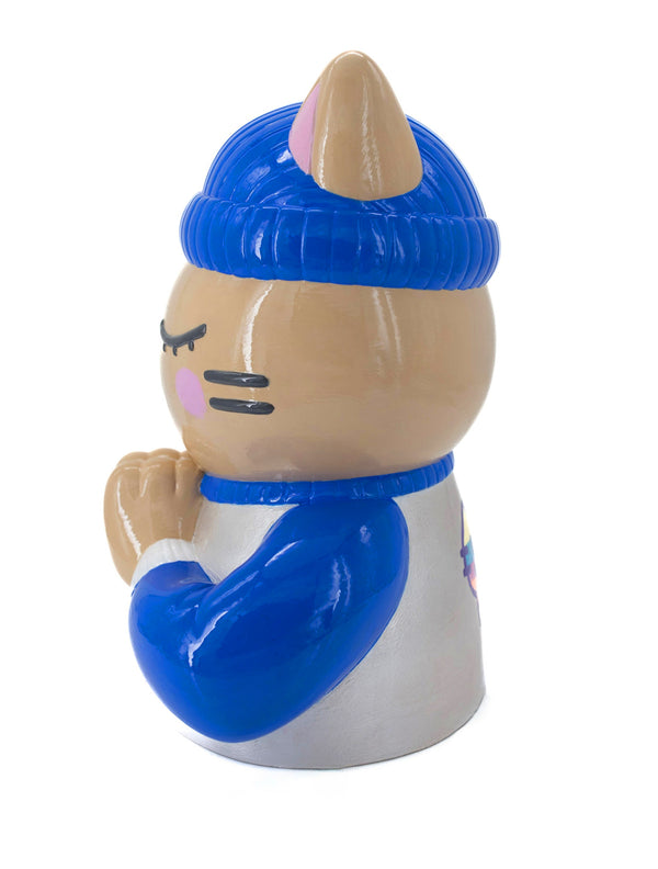 Vue de profil gauche de la sculpture "Foi" par CHANOIR – œuvre originale. Chat beige aux yeux clos, coiffé d’un bonnet bleu vif et vêtu d’un maillot blanc nacré avec manches bleu vif et bordures blanches. Pièce unique peinte à la main, fusion de street art et sculpture contemporaine.