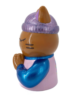 Vue latérale de la sculpture "Justice" par CHANOIR – Œuvre originale. Chat méditatif en position de prière, bonnet violet et pull bleu métallisé, finition peinte à la main. Un objet d’art unique mêlant street art et design contemporain.