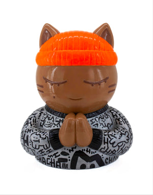 Vue de face de la sculpture collector de CHANOIR, ce chat méditatif porte un tee-shirt gris métallisé avec des graffiti noirs, il est coiffé d'un bonnet orange fluo. Une oeuvre d'art contemporain mêlant pop art, art urbain et figuration libre.