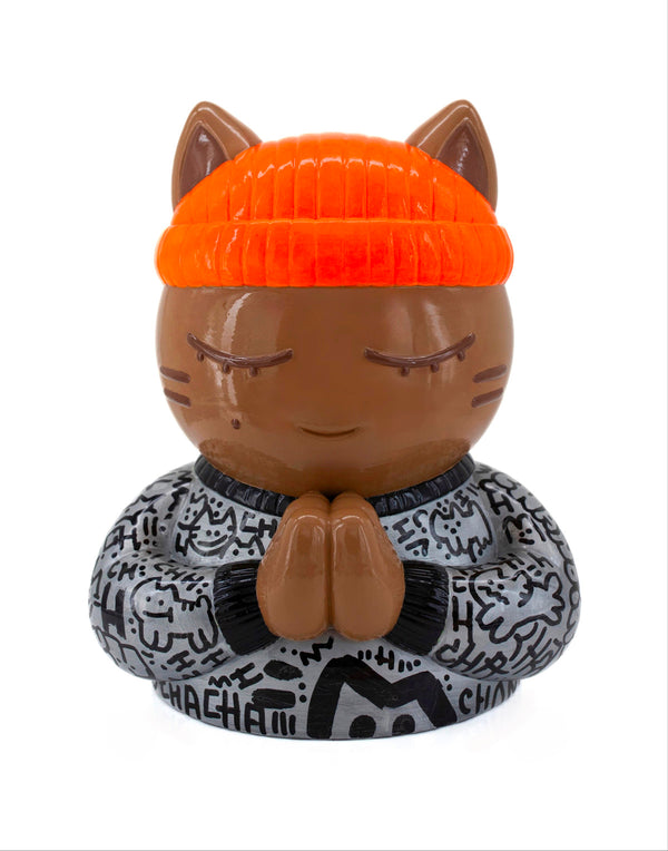 Vue de face de la sculpture collector de CHANOIR, ce chat méditatif porte un tee-shirt gris métallisé avec des graffiti noirs, il est coiffé d'un bonnet orange fluo. Une oeuvre d'art contemporain mêlant pop art, art urbain et figuration libre.