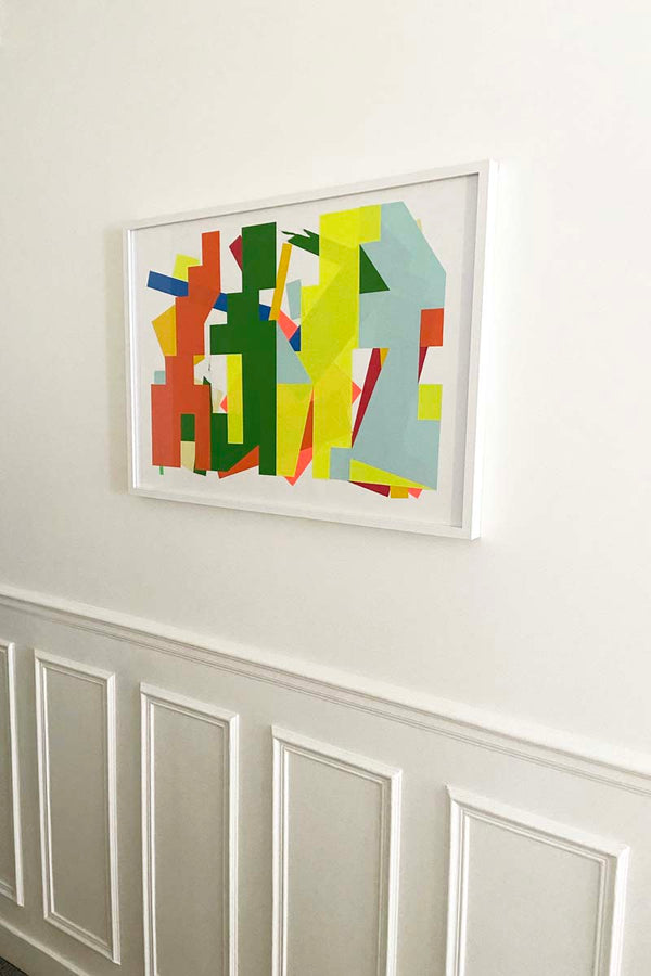 Vue in situ de l’œuvre DBNS Orange vert fluo bleu (2025), collage abstrait 50 × 70 cm de l’artiste contemporain Debens, encadré en blanc sur un mur mouluré, présenté par la Galerie Vermeulen