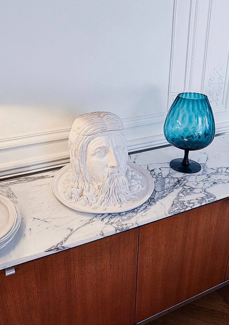 Soupière sculpturale en forme de tête par l’artiste Gérald Schmite, posée sur un buffet en marbre dans un intérieur haussmannien.