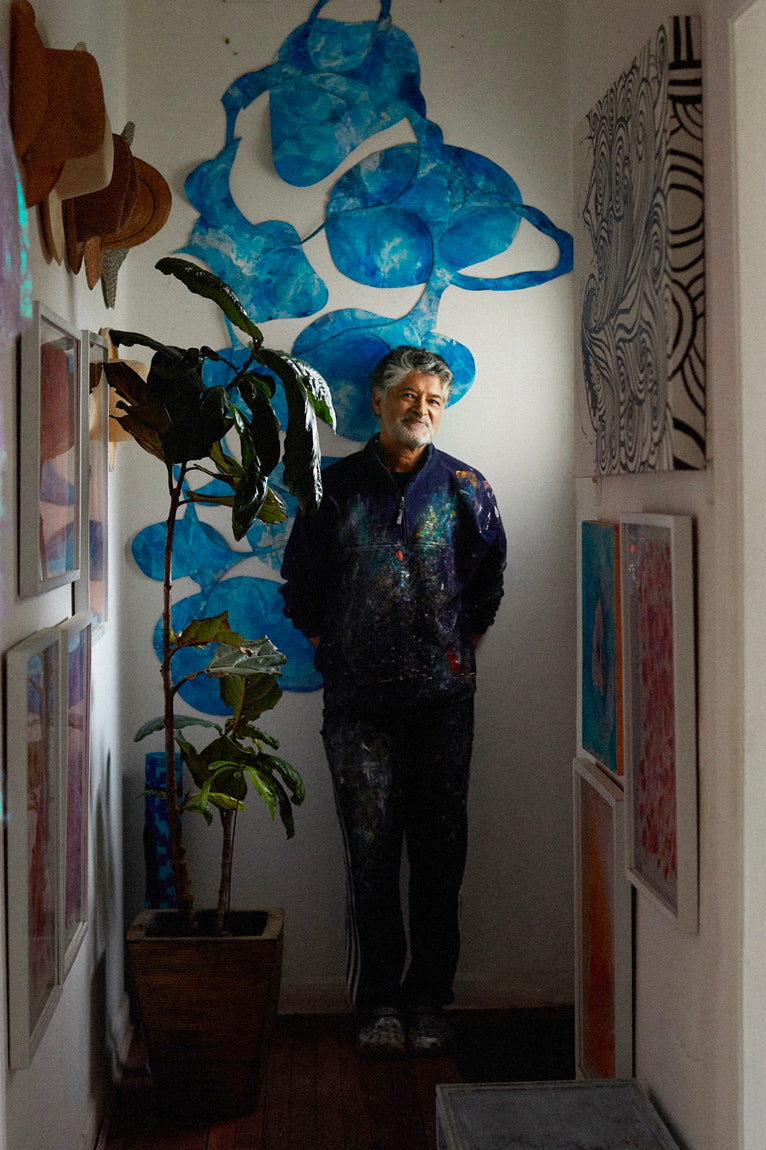 Portait de l'artiste colombien Gustavo Vejarano posant devant un mur orné de ses sculptures. Un artiste abstrait représenté la la Galerie Vermeulen.