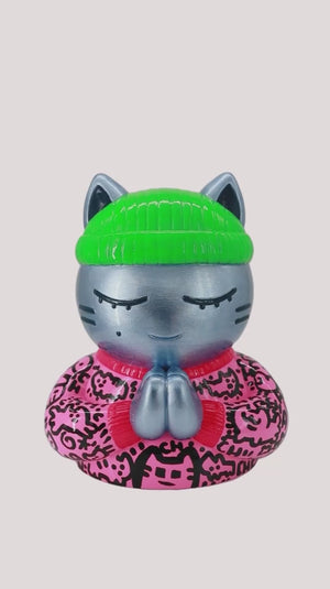 Video de la sculpture de l'artiste Street Art CHANOIR. Un chat au bonnet vert fluo qui prie les mains jointes et les yeux fermés.