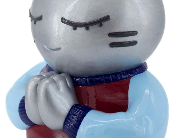 Gros plan de la sculpture contemporaine de Chanoir. Cette œuvre unique, Espérance (2025), en résine, aux nuances argentées, bleues et bordeaux, exprime une sérénité profonde avec son visage aux yeux clos et ses mains jointes. Un design minimaliste et poétique, emblématique du style pop et graphique de l’artiste. Pièce exclusive pour collectionneurs et amateurs d’art. Disponible sur Galerie Vermeulen.
