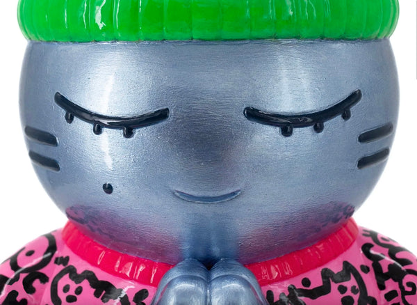 Détail de la sculpture de CHANOIR, représentant un chat aux yeux clos, la peau bleu métallisée, un bonnet vert fluo et un tee-shirt street-art rose, à graffitis noirs.
