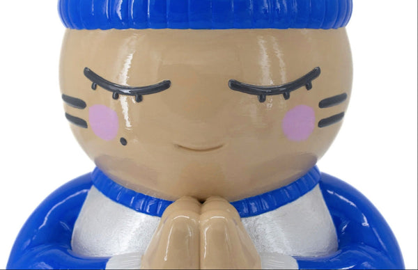Détail de la tête de la sculpture CHANOIR, coiffée d’un bonnet bleu vif, vêtue d’un maillot blanc nacré avec manches bleu vif et orné d’un motif de chat à rayures colorées sur le dos. Pièce unique peinte à la main, fusion de street art et sculpture contemporaine.